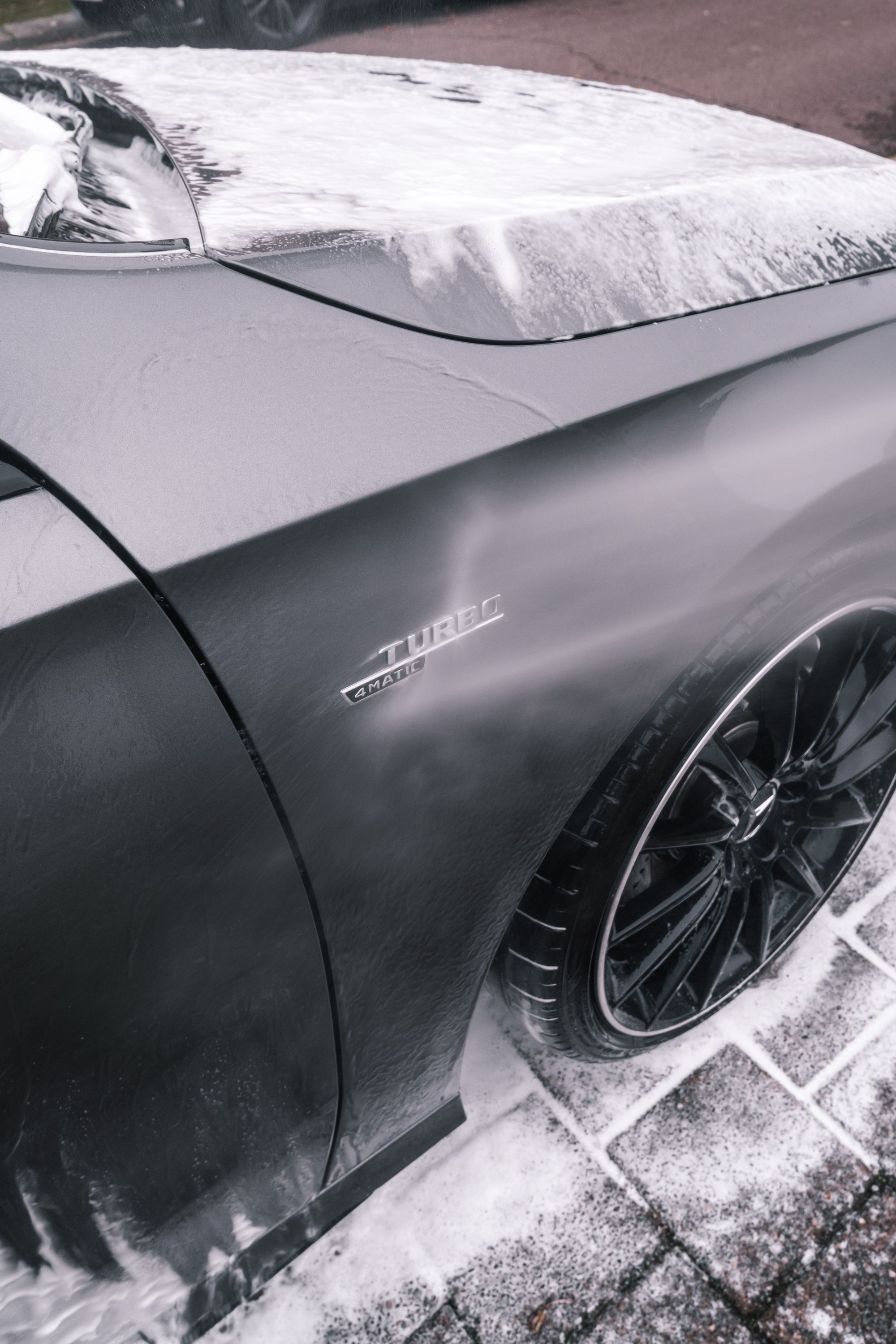 Foam washing across the dark exterior of a car